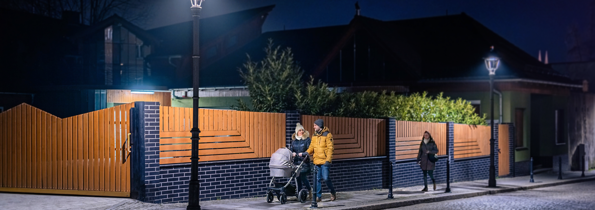 Menschen gehen nachts auf einer gut beleuchteten Strasse.