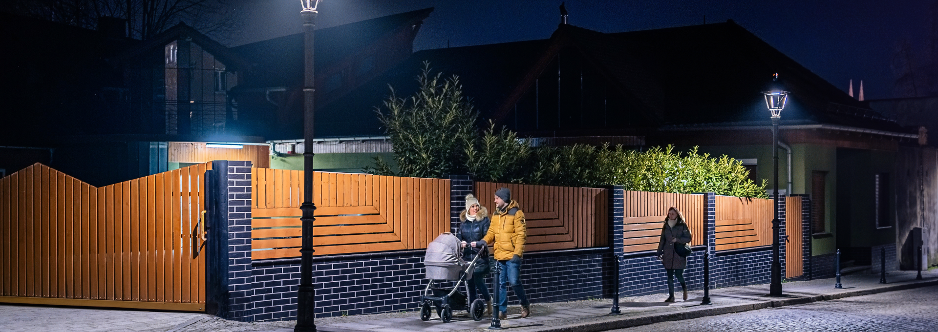 Ludzie spacerujący nocą dobrze oświetloną ulicą.